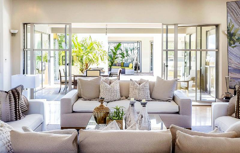 Bright, modern living room with open doors and plush sofas.